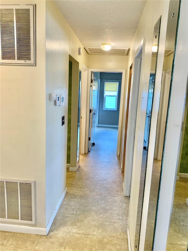 hallway with light tile patterned flooring and a textured ceiling