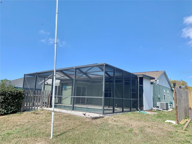 back of house with central AC, a lanai, and a lawn