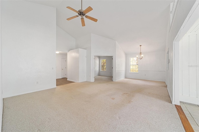 unfurnished living room with light carpet, ceiling fan with notable chandelier, and high vaulted ceiling