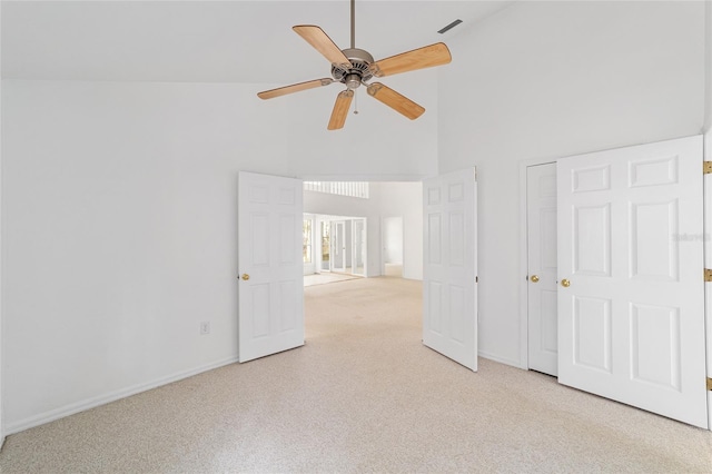 carpeted empty room with ceiling fan and a high ceiling