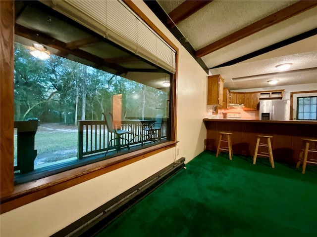 bar featuring lofted ceiling with beams, dark colored carpet, stainless steel fridge, and a textured ceiling