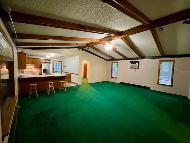 interior space with dark carpet, ceiling fan, lofted ceiling with beams, and a textured ceiling