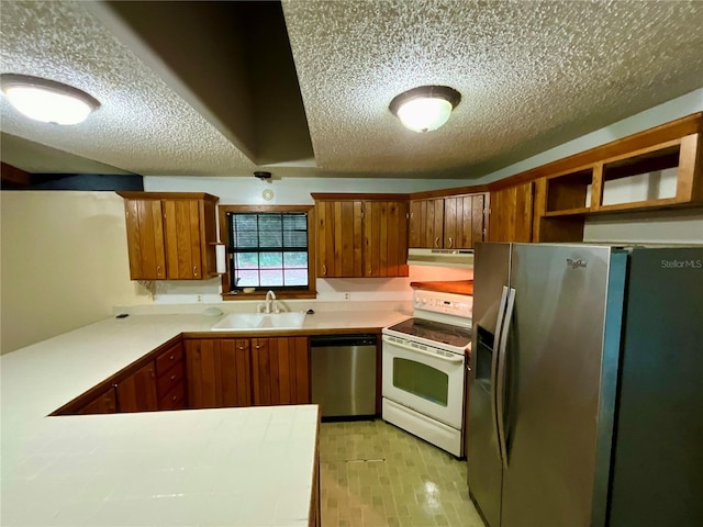 kitchen with stainless steel appliances, sink, a textured ceiling, and kitchen peninsula