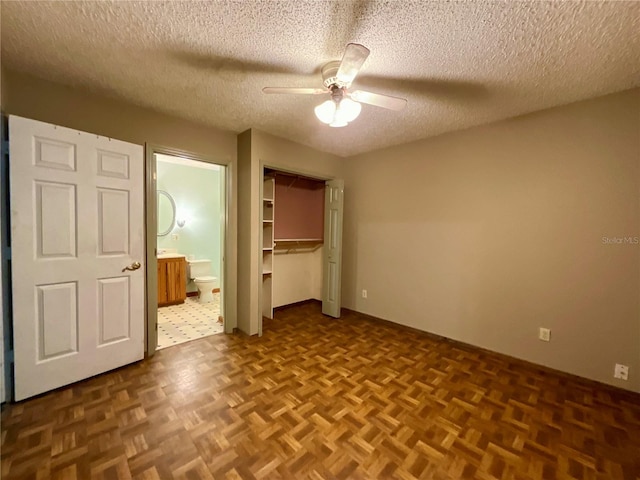 unfurnished bedroom featuring parquet floors, a closet, a textured ceiling, and ensuite bathroom