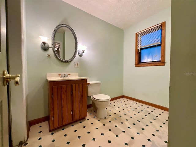 bathroom with vanity, toilet, and a textured ceiling