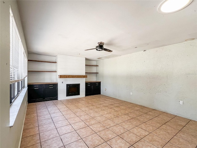 unfurnished living room featuring ceiling fan and a fireplace