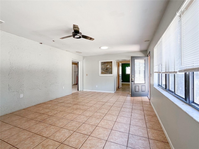 tiled spare room featuring ceiling fan