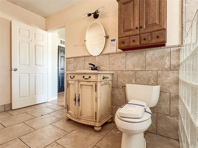 bathroom with vanity, toilet, tile patterned flooring, and tile walls