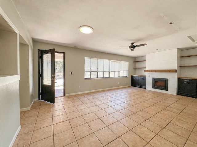 unfurnished living room with light tile patterned floors, a large fireplace, and ceiling fan