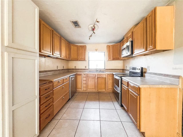 kitchen with light tile patterned flooring, stainless steel appliances, and sink