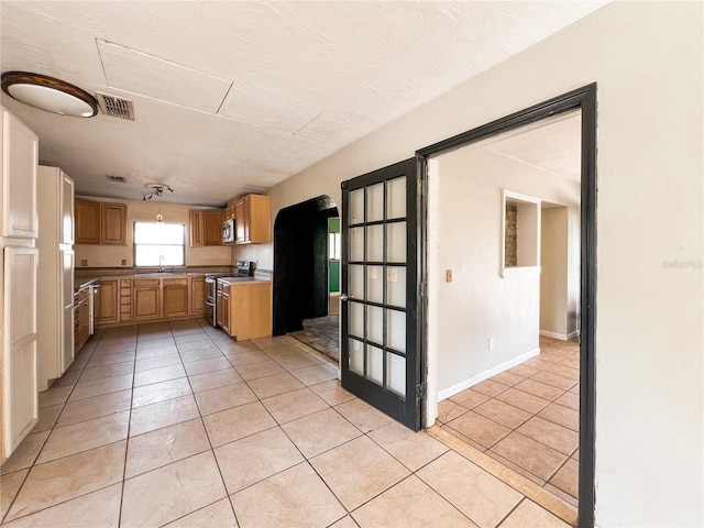 kitchen featuring light tile patterned flooring, appliances with stainless steel finishes, sink, and a textured ceiling