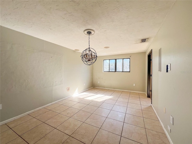 tiled spare room with an inviting chandelier and a textured ceiling