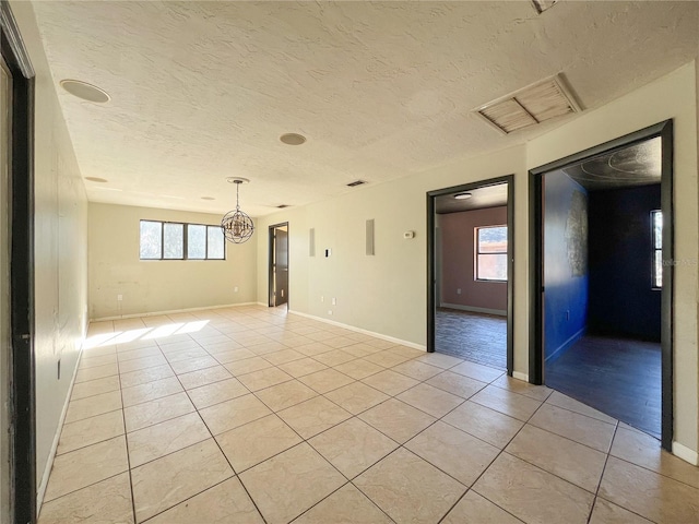 tiled empty room featuring a textured ceiling and a healthy amount of sunlight