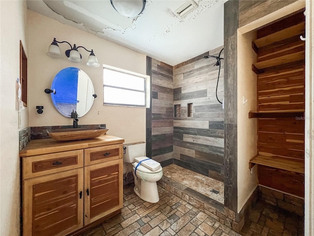 bathroom featuring vanity, toilet, and tiled shower