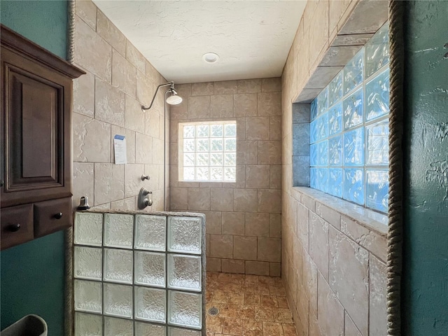 bathroom featuring a tile shower and a textured ceiling