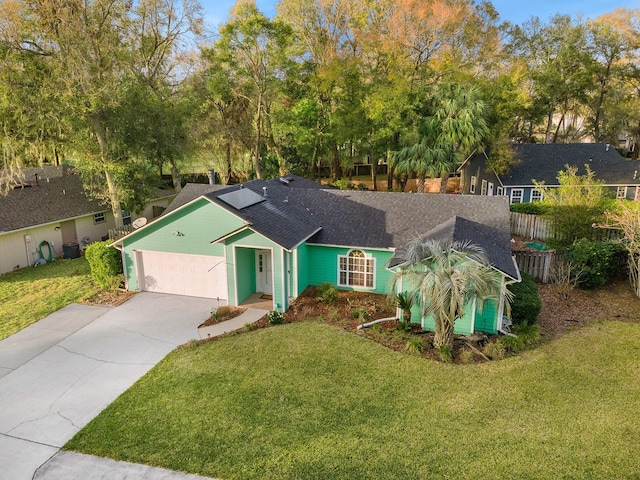 ranch-style home featuring a front yard, fence, driveway, and roof with shingles