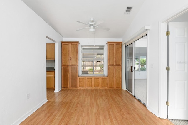 spare room featuring plenty of natural light, visible vents, light wood-style flooring, and a ceiling fan