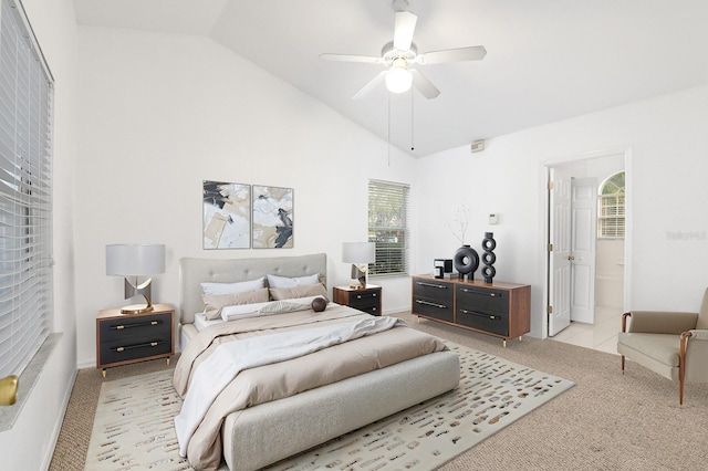 bedroom with high vaulted ceiling, connected bathroom, a ceiling fan, and light colored carpet