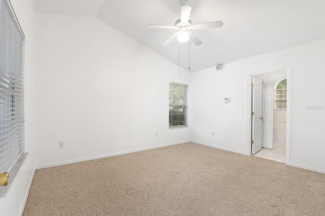 interior space with lofted ceiling, a ceiling fan, light carpet, connected bathroom, and baseboards