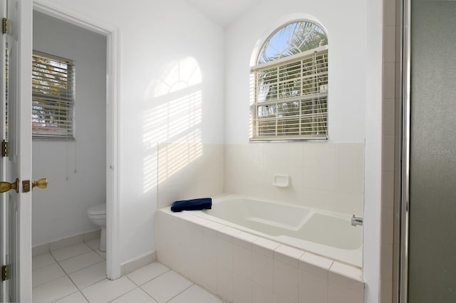 full bathroom with tile patterned flooring, baseboards, a garden tub, and toilet