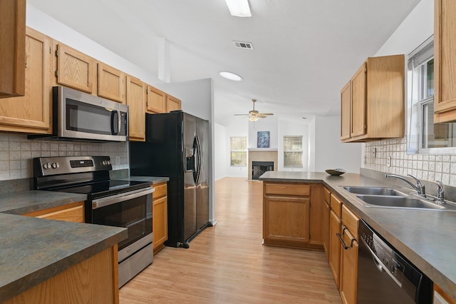 kitchen featuring visible vents, light wood-style floors, a sink, a peninsula, and black appliances