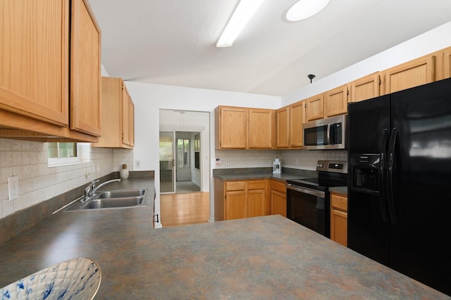 kitchen with decorative backsplash, dark countertops, appliances with stainless steel finishes, vaulted ceiling, and a sink