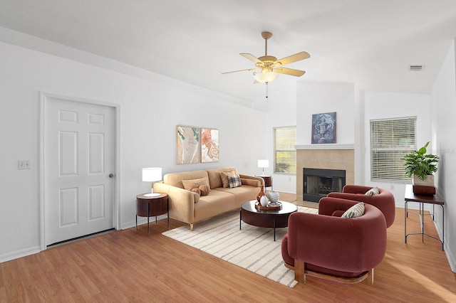 living area featuring lofted ceiling, visible vents, a fireplace, and wood finished floors