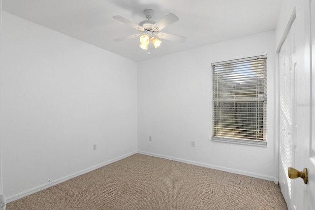 spare room featuring light carpet, ceiling fan, and baseboards