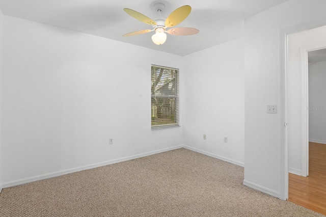 spare room with light carpet, a ceiling fan, and baseboards