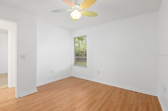 spare room with ceiling fan, light wood-style flooring, and baseboards