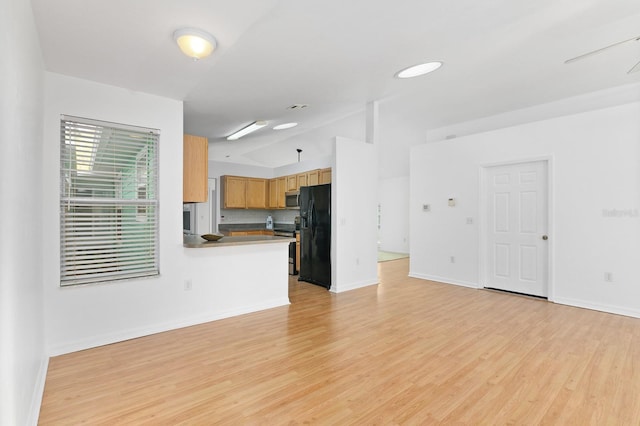 unfurnished living room featuring vaulted ceiling, light wood-style flooring, and baseboards