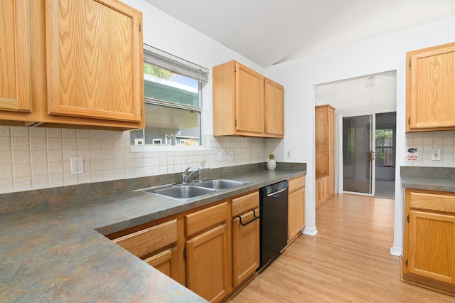 kitchen with light wood-style flooring, a sink, vaulted ceiling, dishwasher, and dark countertops