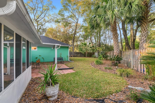 view of yard featuring a sunroom, a fenced backyard, and a patio