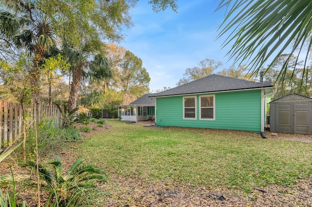 view of yard featuring a sunroom, fence, an outdoor structure, and a shed