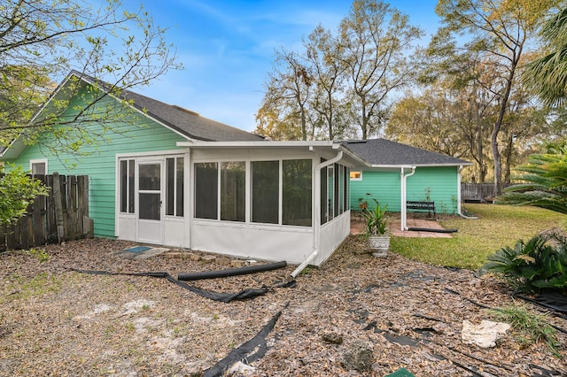 rear view of property with a sunroom, fence, and a yard