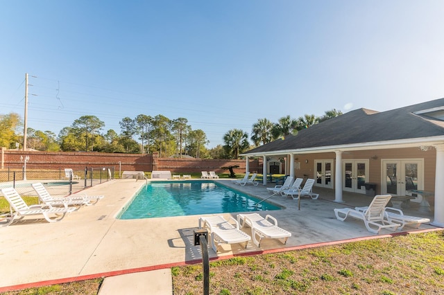 pool with fence, a patio, and french doors