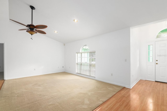 unfurnished living room featuring light carpet, light wood finished floors, baseboards, and high vaulted ceiling