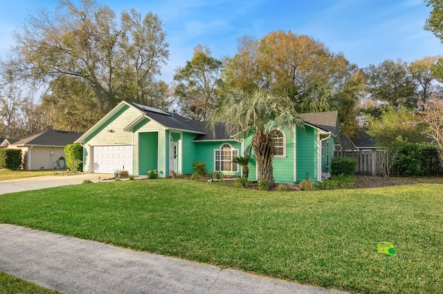 view of front of property with a front lawn, roof mounted solar panels, fence, concrete driveway, and an attached garage