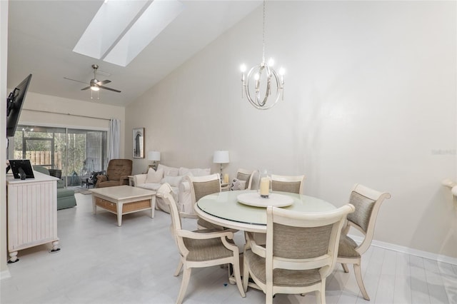 dining room with ceiling fan with notable chandelier, high vaulted ceiling, and a skylight