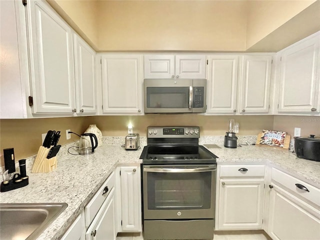 kitchen with white cabinetry, appliances with stainless steel finishes, and light stone countertops