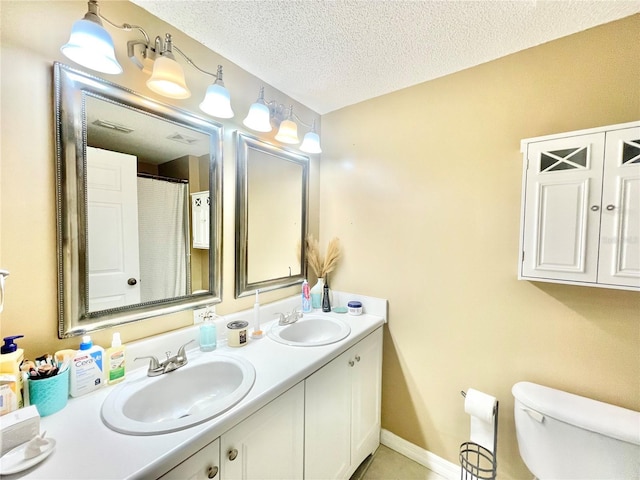 bathroom with vanity, toilet, and a textured ceiling