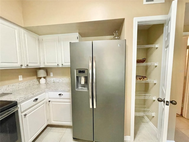 10000 SW 52nd Ave Unit 103, Gainesville, FL 32608 - kitchen with appliances with stainless steel finishes, light tile patterned flooring, white cabinetry, and visible vents