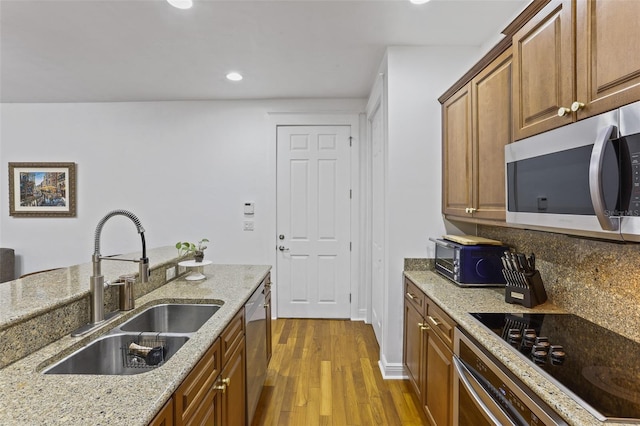 kitchen with sink, dark wood-type flooring, appliances with stainless steel finishes, tasteful backsplash, and light stone countertops