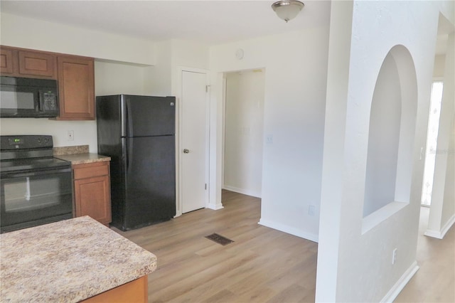 kitchen with light hardwood / wood-style floors and black appliances