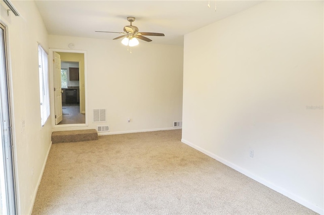 empty room featuring ceiling fan and light colored carpet