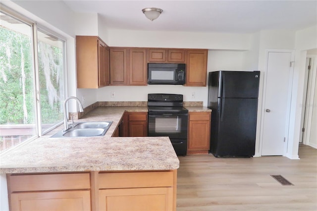 kitchen featuring plenty of natural light, sink, light hardwood / wood-style floors, and black appliances