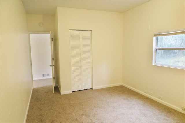 unfurnished bedroom with light carpet and a closet