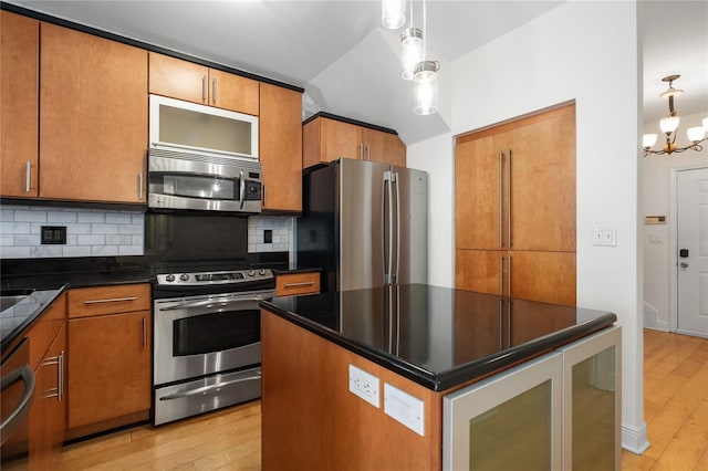 kitchen with appliances with stainless steel finishes, decorative backsplash, hanging light fixtures, a notable chandelier, and light hardwood / wood-style floors