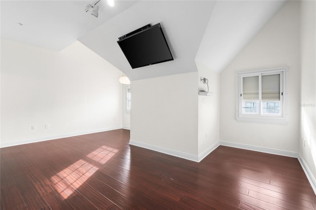 unfurnished living room with lofted ceiling, dark hardwood / wood-style flooring, and rail lighting