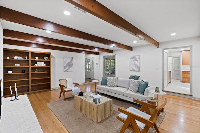 living room with beamed ceiling and light hardwood / wood-style flooring